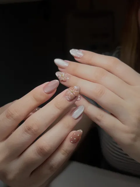 Nude almond nails with a 3D peach flower, white dots and a soft chrome finish
