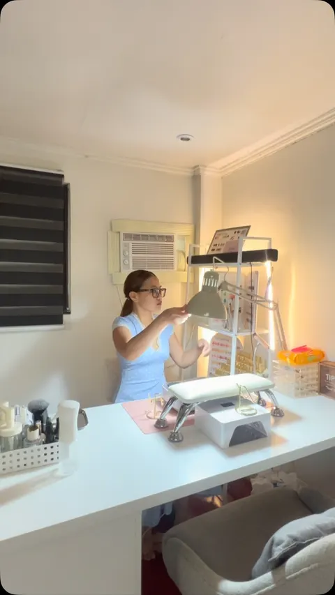 Celeste adjusting the lamp at her home-studio nail desk